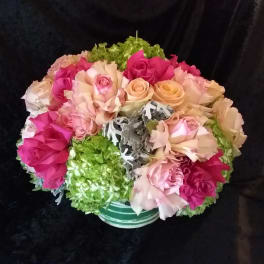 Bouquet of pink and peach roses with green hydrangeas in a striped vase