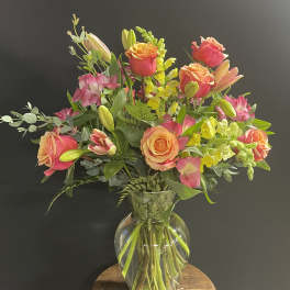 Bouquet of pink and peach roses with lilies in a clear glass vase