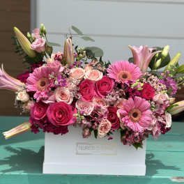 Pink roses and gerbera daisies arranged in a white box