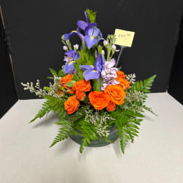 Orange roses and purple irises arranged in a low vase