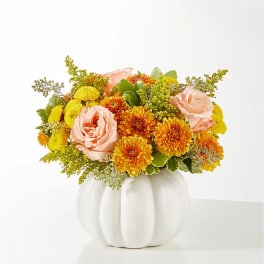 Pink roses and yellow-orange mums in a white pumpkin vase