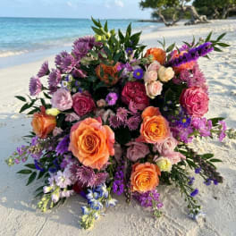 Large bouquet of orange, pink, and purple flowers on a beach