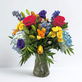 Colorful bouquet of roses, lilies, and hydrangeas in a clear glass vase