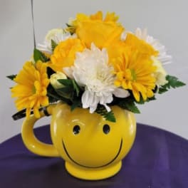 Yellow and white daisy bouquet in a smiley-face mug