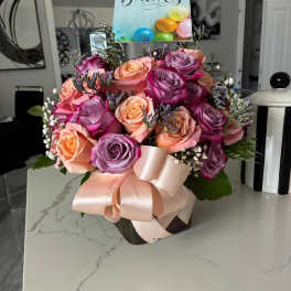 Bouquet of pink, peach, and lavender roses with a birthday card and ribbon