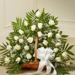White roses in a wicker basket with a large white bow