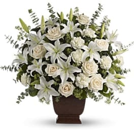 White lilies and roses arranged in a brown urn vase