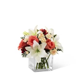 Bouquet of white lilies and coral roses in a clear glass vase