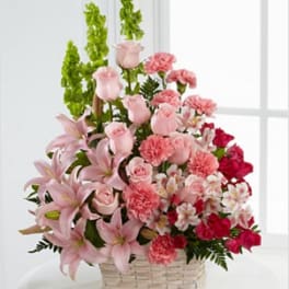 Pink lilies, roses, and carnations in a woven basket