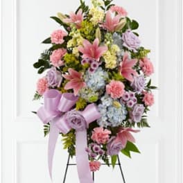Standing floral spray with pink lilies, lavender roses, and pastel ribbons
