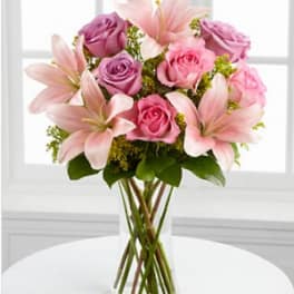 Pink roses and lilies arranged in a clear glass vase