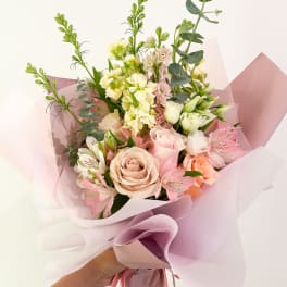 Handheld bouquet of pink and cream roses with pale filler flowers