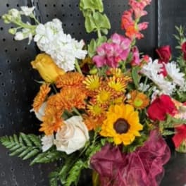 Mixed bouquet in a yellow vase with sunflowers, roses, and snapdragons