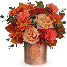 Orange and peach bouquet in a copper vase with leaf cutout