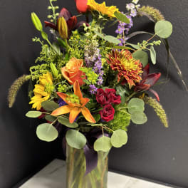 Mixed bouquet in a glass vase with roses, lilies, and sunflowers