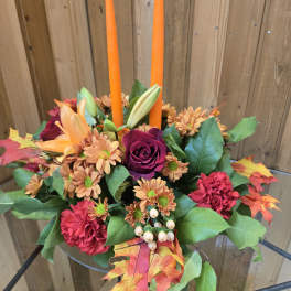 Autumn floral centerpiece with orange candles in a low glass bowl