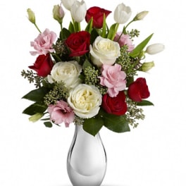 Bouquet of red and white roses with pink blooms in a clear glass vase
