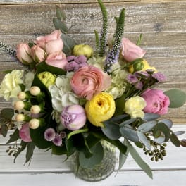 Pastel bouquet of roses, ranunculus, and hydrangeas in a clear glass vase
