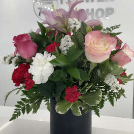 Pink lilies and roses arranged in a black vase