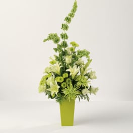 Tall green and white floral arrangement with lilies, roses, and mums in a lime green rectangular vase