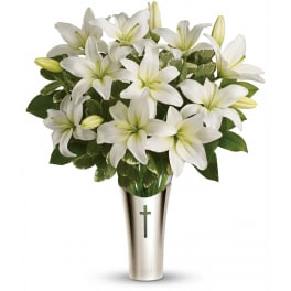 White lily arrangement in a tall silver vase with a cross emblem
