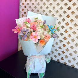 Pastel mixed bouquet wrapped in light blue paper with a ribbon