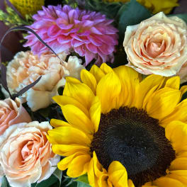Close-up bouquet with a sunflower, peach roses, and a pink dahlia