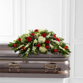 Red roses and white flowers arranged on top of a casket