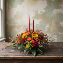 Low floral centerpiece with red taper candles and mixed autumn blooms