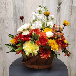 Mixed fall flowers in a brown basket with plaid ribbon
