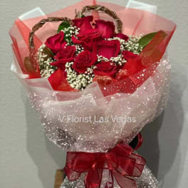 Bouquet of red roses wrapped in pink and white mesh with a red ribbon