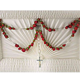 Rosary with red rose buds draped over a white pleated cloth