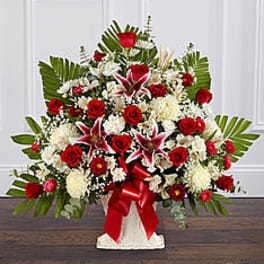 Large red and white floral arrangement in a white vase with a red ribbon