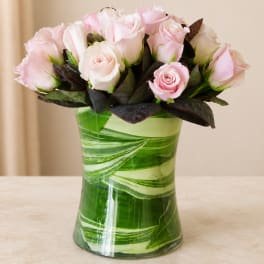 Pink and white roses arranged in a green glass vase
