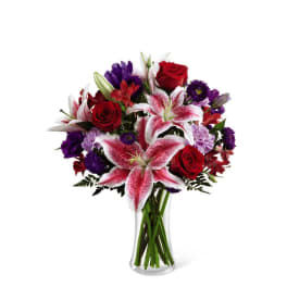 Mixed bouquet of red roses and pink lilies in a clear glass vase