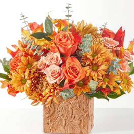 Autumn bouquet of orange roses and yellow daisies in a carved vase