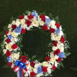 Circular floral wreath with red, white, and blue flowers on a stand