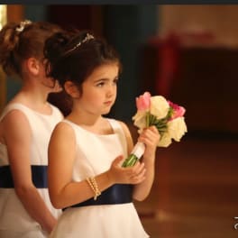 Two girls in white dresses holding small flower bouquets