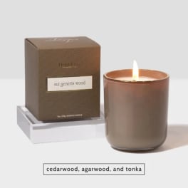 Lit scented candle in a glass jar beside its box