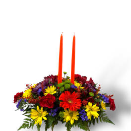 Colorful floral centerpiece with two orange taper candles