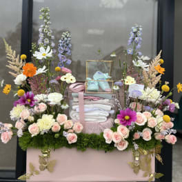 Pastel floral gift box with baby shoes and folded blankets