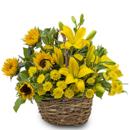 Yellow lilies and sunflowers arranged in a wicker basket