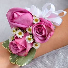 Pink rose wrist corsage with small white daisies and a white ribbon bow