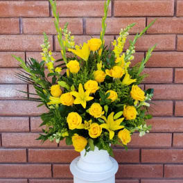 Yellow roses and lilies arranged in a white vase