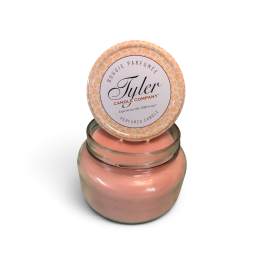 Pink scented candle in a glass jar with a patterned lid