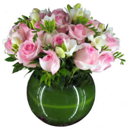 Pink roses and white flowers arranged in a green glass vase