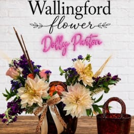 Arrangement of cream and purple flowers in a tortoiseshell vase with ribbon