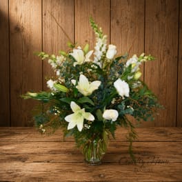 White lilies and roses arranged in a clear glass vase