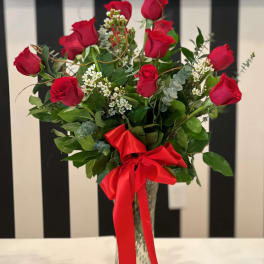 Red roses arranged in a clear glass vase with a red ribbon