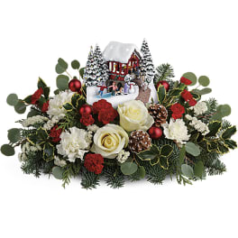 Christmas floral centerpiece with roses, carnations, and a winter village decoration